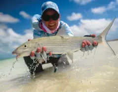  ??  ?? (Clockwise from top left) Jen Lofgren offers up a bonefish; a bent rod is a happy rod; the endless flats of Christmas Island; guide James points the way for Kay Dushane; Jenny West cradles a trigger.