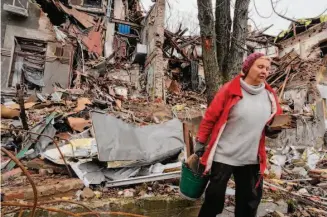  ?? Efrem Lukatsky/Associated Press ?? A resident carries wood scraps to build an outdoor fire for cooking near her damaged house in Sloviansk in the Donetsk region. The neighborho­od was devastated by Russian shelling attacks.