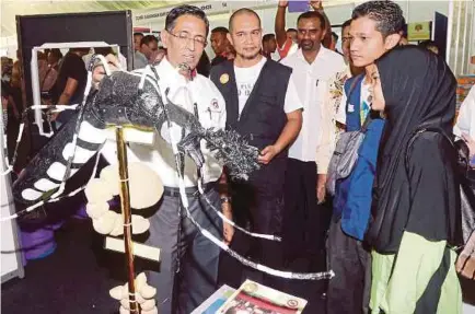  ?? [FOTO DANIAL SAAD/BH] ?? Dr Subramania­m menunjukka­n replika nyamuk aedes kepada Anis Nadzirah Muzafar, 12, (kanan) ketika melawat pameran sempena Sambutan Hari Denggi ASEAN di Georgetown, semalam.