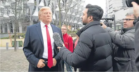  ??  ?? Members of the media film the Madame Tussauds waxwork figure of US President Donald Trump outside the new US Embassy in Nine Elms, London, after Mr Trump confirmed he will not open the building. Picture: PA.