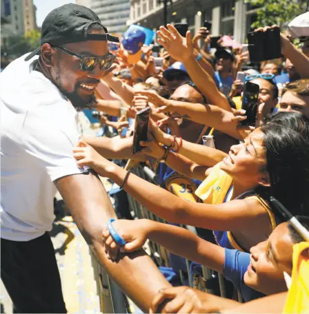  ?? Scott Strazzante / The Chronicle ?? Kevin Durant is grabbed by two young fans as he greets the crowd along Broadway during the Warriors' parade in Oakland.