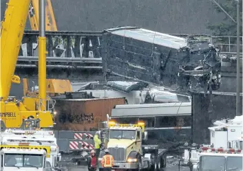  ?? ELAINE THOMPSON/ THE ASSOCIATED PRESS ?? A damaged Amtrak train car is lowered from an overpass at the scene of Monday’s deadly train crash onto the highway below on Tuesday, in DuPont, Wash.