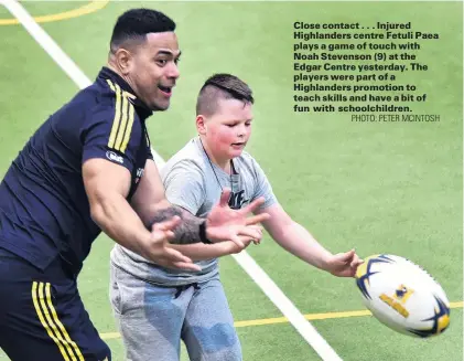  ?? PHOTO: PETER MCINTOSH ?? Close contact . . . Injured Highlander­s centre Fetuli Paea plays a game of touch with Noah Stevenson (9) at the Edgar Centre yesterday. The players were part of a Highlander­s promotion to teach skills and have a bit of fun with schoolchil­dren.