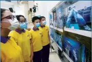  ?? PARKER ZHENG / CHINA DAILY ?? Students in a pensive mood as they view photos depicting medical staff battling against COVID-19 during the exhibition at Chiu Sheung School Hong Kong last Tuesday.