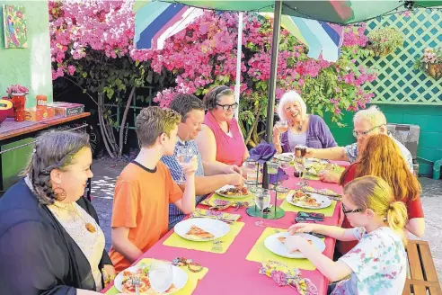  ?? EDUARDO CONTREAS/SAN DIEGO UNION-TRIBUNE ?? Members of the Haven family enjoy an al fresco pizza party in the central patio located between the apartment complex and Sharon’s bungalow.