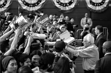  ?? AP Photo/Damian Dova rganes ?? Democratic presidenti­al candidate Sen. Bernie Sanders, I-Vt., signs autographs at the Valley High School in Santa Ana, Calif., on Feb 21.