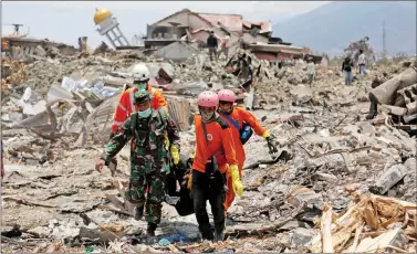  ?? REUTERS ?? Rescue workers and a soldier remove a victim of last week’s earthquake in the Balaroa neighbourh­ood in Palu, Central Sulawesi, Indonesia on Saturday.