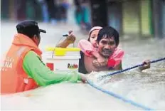  ??  ?? Negotiatin­g the floods A father carrying his daughter on his back holds on to a rope as they make through the flood waters in Tumana.
AFP