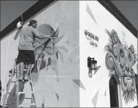  ?? Jacob Ford/Odessa American via AP ?? Artist: Muralist Benito Mendoza, aka Deko_Uno, paints a mural of a burger on the north side of Curb Side Bistro Tuesday, May 28, 2019 in Odessa, Texas. Mendoza grew up in a dangerous neighborho­od of Juarez, Mexico, where gang activity and graffiti go hand in hand. While most people in his neighborho­od would use spray cans to mark their territory Mendoza was inspired by the power it had as a social purpose. Mendoza said he was highly influenced by the 20th century Mexican painter Diego Rivera. Rivera set an example as a community activist who painted the working class and helped establish the Mexican mural movement through his public murals.