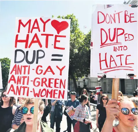  ??  ?? There were protests outside Parliament over the weekend as DUP leader Arlene Foster, left, prepared to fly to London tomorrow to finalise a possible deal with Theresa May