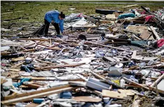  ?? DAVID GOLDMAN / ASSOCIATED PRESS ?? Kayla Causey sifts through debris on Tuesday while helping her mother retrieve personal items after a tornado destroyed her home in Beauregard, Ala.