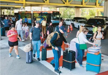  ?? MIKE STOCKER/SOUTH FLORIDA SUN SENTINEL ?? Passengers cross the street as traffic backs up in the terminal for passenger pickup and drop-off at Fort Lauderdale-Hollywood Internatio­nal Airport on Friday.