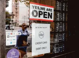  ?? Jessica Christian/The Chronicle ?? Many Oakland merchants, including the Suit Lounge downtown, no longer accept cash payments due to a surge in robberies.