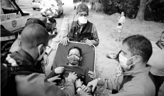  ?? AP ?? Wearing masks to curb the spread of the new coronaviru­s, Angels of the Road volunteer paramedics take a boy on a stretcher to their ambulance after he was involved in a motorcycle accident in Caracas, Venezuela, on February 4.