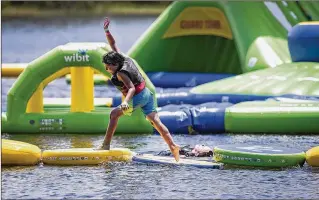  ??  ?? Japheth Montejo, 11, of Jupiter, runs the water obstacle course as Braxton Newman, 14, of West Palm Beach, cools off in the water at the Aqua Park at Okeeheelee Park in West Palm Beach on Thursday. Shark Wake Park’s floating Aqua Park has been open for less than a week at Okeeheelee Park, but people already are expressing concerns about potential dangers there brought by alligators, among others.