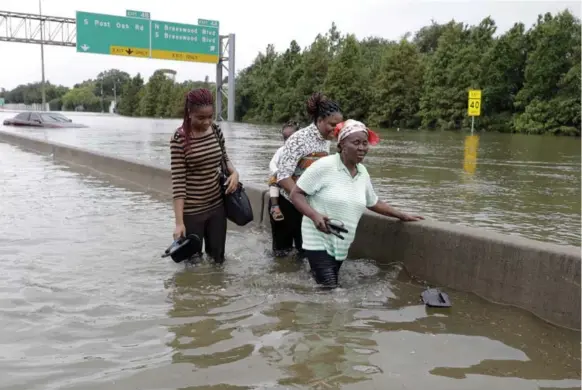  ?? DAVID J. PHILLIP/THE ASSOCIATED PRESS ?? Evacuees wade down a flooded section of an interstate in search of higher ground as remnants of hurricane Harvey sent devastatin­g floods pouring into Houston Sunday.