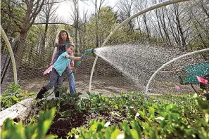  ?? The Associated Press ?? ■ Jack Holden waters flower plants with his mother Ellie, at their home May 12 in Proctor, Vt. After fleeing one of the most destructiv­e fires in California, the Holden family wanted to find a place that had not been so severely affected by climate change and chose Vermont.