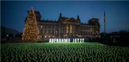  ?? AFP/VNA Photo ?? Thousands of green candles are lit in front of the Reichstag building in Berlin, in an action set up to draw attention to the refugees' situation at the Polish-belarusian border, on November 28, 2021.