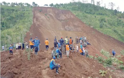  ?? — Reuters ?? Rescuers look for people feared to be buried after a landslide triggered by heavy rain hit Banaran village in Ponorogo, East Java province.