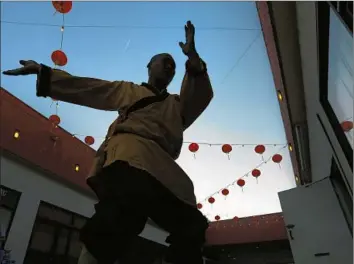  ?? Photog r aphs by
Rick Loomis
Los Angeles Times ?? MASTER SHI YANXU teaches children kung fu outdoors at the Far East Plaza in Chinatown. Yanxu ran away from home at a young age to train as a monk at the Shaolin Temple.