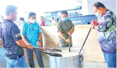  ??  ?? Noor Alam (second left) cooking ‘bubur lambuk’ to be distribute­d to frontliner­s on duty in Sandakan.