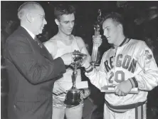  ?? University of Oregon 1939 ?? Oregon’s Bobby Anet (right) is presented with the first NCAA championsh­ip trophy by Big Ten Commission­er John Griffith (left) as Ohio State’s Jimmy Hull watches on March 27, 1939.