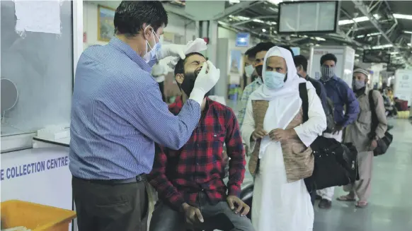  ?? AP ?? A health worker takes a nasal swab sample from a passenger during testing at a railway station in Jammu on Saturday