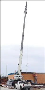  ?? Westside Eagle Observer/MIKE ECKELS ?? A constructi­on crane lifts a steel beam into place next to the old Decatur High School cafeteria. The steel skeleton of the new cafeteria started going up on Dec. 28 and is expected to be complete by summer 2021.