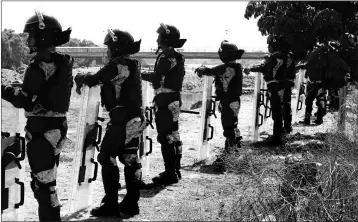  ?? ASSOCIATED PRESS ?? MEXICAN NATIONAL GUARDSMEN stand along the Mexican side of the bank of the Suchiate River near Ciudad Hidalgo, Mexico, on the border with Guatemala, Tuesday, Jan. 21. Hundreds of Central American migrants who waded across the river into Mexico in hopes of eventually reaching the U.S. were sent back to their homeland or retreated across the border Tuesday after Mexican troops blocked their way.