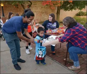  ?? File Photo/BEN GOFF ?? Abarca, 3, with uncle Erick Diaz of Rogers gets candy from Ashley Sayers with the Rogers Historical Museum during a previous Main Street Rogers Goblin Parade in downtown Rogers.