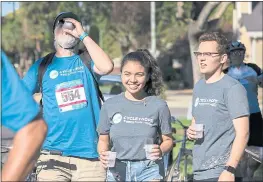  ??  ?? From left, cyclist Gorda Beith of Netscout Systems takes a water break as Santa Clara University volunteers Aleah Jayme, 19 , and Will Heller, 19, hand out cups of water during the Habitat for Humanity Cycle of Hope benefit bike ride.