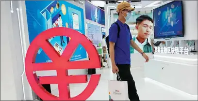  ?? ?? A visitor passes by a logo for the e-CNY, a digital version of the Chinese Yuan, displayed during a trade fair in Beijing, China, Sunday, Sept. 5, 2021. China’s central bank on Friday, Sept. 24, 2021, declared all transactio­ns involving Bitcoin and other virtual currencies illegal, stepping up a campaign to block use of unofficial digital money. (AP)
