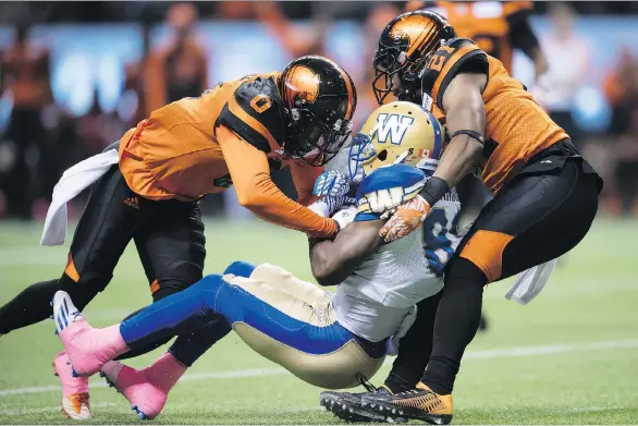  ?? DARRYL DYCK/ THE CANADIAN PRESS ?? B.C.’s Loucheiz Purifoy, left, and Ryan Phillips engulf Winnipeg’s Clarence Denmark at B.C. Place. The Lions host the red-hot Eskimos today.