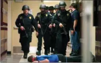  ?? RICHARD ALAN HANNON — THE ADVOCATE VIA AP ?? In this photo, Baton Rouge Police Department SWAT team members walk down a McKinley Middle Magnet School hallway past a fire academy member playing the role of a victim during a simulated hostage situation in Baton Rouge, La. High-tech hardware installed by NetTalon Security Systems reduced “casualties” during the exercise, according to then-principal Herman Brister. But in hindsight, he said he would have rather hired an armed resource officer.