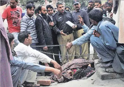  ??  ?? BABARITY: As the victim’s body lies in a court square, police interview witnesses to the stoning..