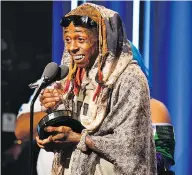  ?? PARAS GRIFFIN / GETTY IMAGES FOR BET ?? Rapper Lil Wayne cradles his award onstage during the BET Hip Hop Awards on Saturday in Miami Beach.