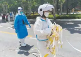  ?? ?? A police officer removes cordon tapes from a street in Shanghai as the city further eases COVID-19 restrictio­ns. — Reuters