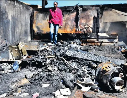  ?? PICTURES: ITUMELENG ENGLISH ?? HAUNTING: A neighbour, Zie Kapo, assesses the scene where three siblings between 11 months and five years died in a shack fire in Snake Park, Soweto, in the early hours of yesterday. The children’s parents sustained burns and are recovering after being...