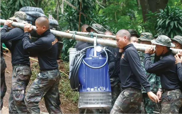  ?? AFP ?? A group of soldiers carries a haven pump on bamboo sticks to help drain the rising flood water in the cave in Mae Sai, Chiang Rai province, in northern Thailand . —