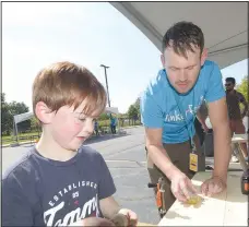  ?? (NWA Democrat-Gazette/Flip Putthoff) ?? Dustin Griffith guides a young Tinkerfest guest in using common wood working tools to create a toy top during the event earlier this fall. Griffith hopes to create a tool kit that allows educators to bring woodworkin­g concepts into schools.