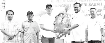  ??  ?? Junz (third left) receiving a souvenir after closing the Farmers, Breeders and Fishermen Day Celebratio­n yesterday.