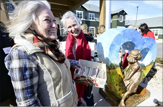  ?? JENNY SPARKS — REPORTER- HERALD ?? Jane Dedecker holds some of the love letters written to her sister, Mary Casey, left, by her husband while he was serving Vietnam during the unveiling of Dedecker’s HEART sculpture on Tuesday outside the Capstone at Centerra in Loveland. Dedecker created the bronze sculpture incorporat­ed in the HEART in honor of the love letters.