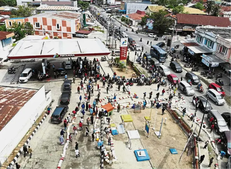  ??  ?? Long and winding fuel stop: An aerial image showing earthquake-affected residents queueing for petrol in Palu following the earthquake and tsunami that devastated the area. — AFP