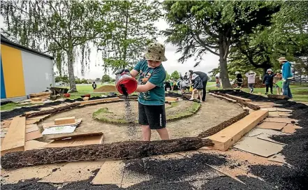  ?? ?? Pupil Lucas Leckie helping pour the soil at the new learning area. Right, Tom Baylis, 3, and Freddie Baylis, 5, having fun shovelling mulch.