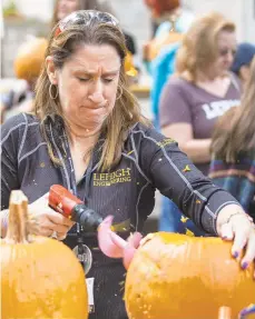  ??  ?? Christine Seymour of East Lyme, Connecticu­t, uses a drill to carve her pumpkin.
