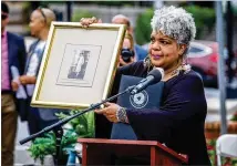  ?? STEVE SCHAEFER FOR THE ATLANTA JOURNAL-CONSTITUTI­ON ?? Inger Williams holds up a photograph of her aunt, Willie Williams, widow of Gwinnett County lynching victim Charles Hale, during a soil collection ceremony in Lawrencevi­lle earlier this month.