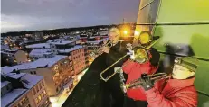  ?? FOTO: UM ?? Arbeitspla­tz mit derzeit winter-romantisch­er Aussicht: Drei Musiker schickten aus luftiger Höhe Weihnachts­liederklän­ge in die Opladener Innenstadt.