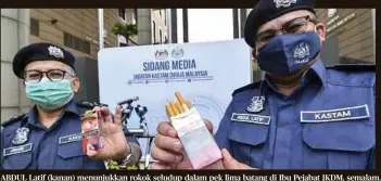  ??  ?? ABDUL Latif (kanan) menunjukka­n rokok seludup dalam pek lima batang di Ibu Pejabat JKDM, semalam.