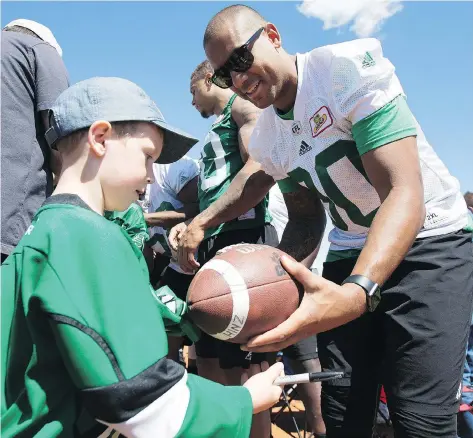  ?? KAYLE NEIS ?? Spencer Moore signs a ball for Ben Hinz during a Saskatchew­an Roughrider practice and autograph session in Humboldt, on Sunday.