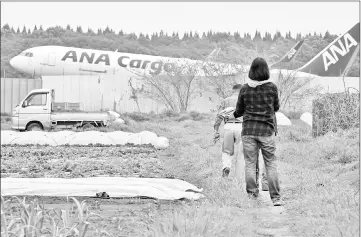  ??  ?? Farmers working in a farm beside the expanding Narita airport,Tokyo’s main internatio­nal gateway, in Chiba prefecture. Takao Shito’s farm is almost surrounded by Narita airport, and jets from around the world roar down right next door to his rows of...